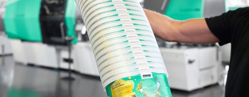 Smarte Spritzgießmaschinen wie diese Allrounder von Arburg können auch Rezyklate in schwankenden Qualitäten verarbeiten. Etwa solche IML-Becher mit digitalem Wasserzeichen, die auf einem Allrounder 820 H in Packaging-Ausführung produziert wurden. - Bild: Arburg