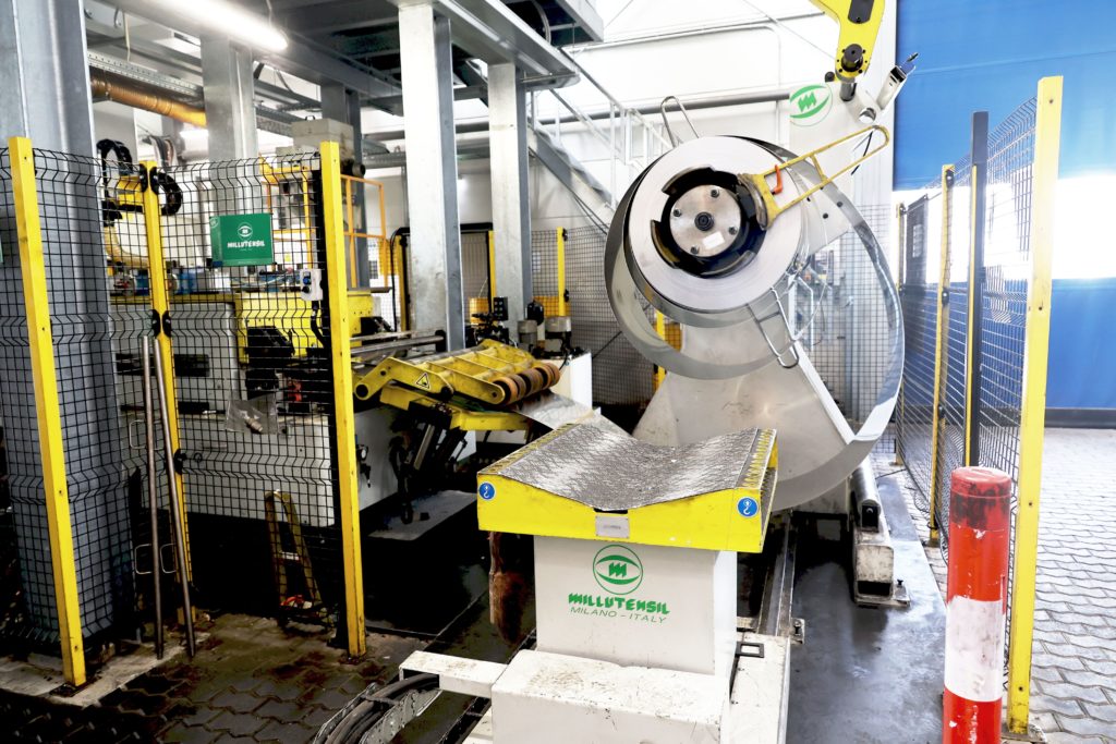 Die Abwickelhaspel von Millutensil kann große Blechcoils aufnehmen. Die Restmenge hier wird in der leistungsfähigen Produktionslösung bald verarbeitet sein. Die Zuführung erfolgt wohldosiert und zuverlässig – die Sicherheit der Bediener wird bei Millutensil ganz groß geschrieben.– Bild: Pergler Media