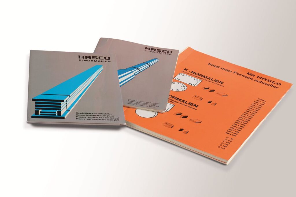 Hasco-Kataloge mit den markanten orangefarbenen Ordnerrücken stehen auch heute noch trotz Digitalisierung an vielen Arbeitsplätzen in der Konstruktion oder im Werkzeugbau. Nach der Erfindung des Normalien-Baukastensystems 1960 erschien im Jahr 1967 die gedruckte Auflage des weltweit ersten Normalien-Kataloges. Die Premierenauflage umfasste anfangs gerade einmal schlanke 50 Seiten. - Bild: Hasco